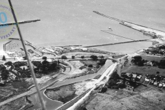 Aerial of harbour from South West. Dredger pumping to reclamation. Canal being formeed with temporary cofferdams. January 1958