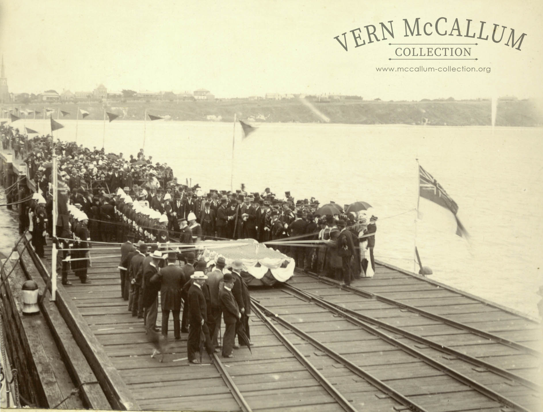 Official Opening of the New Pier, February 13th, 1902.
Mr K.S. Anderson suggests that the following people were probably present, at the Official Opening by Hon W. McCulloch --
The Mayor of Portland, Cr Wm Hanlon.
Councillors: (Dr) Levis, E. Adams, Wm Heaney, E.W, Harvey, G.H. Tulloh, J. Wiltshire, Ben Davis, W.L. Gray.
Town Clerk and Surveyor, Mr T.E.C. Henry.
Shire President,
Shire Secretary, Mr T. Tulloh and Shire Engineer, Mr C.C.P. Wilson.
Harbour Master, Pilot, of Portland, Captain Beaumont.
Mr Samuel Winter Cooke of "Murndal" elected 1901 as Member for Wannon.
Mr Ewan Cameron M.L.A (Re-elected 1900) Member for Portland, 1902.
Mr H.N.Reid, Manager of Freezing Works.
Mr H.J.M. Campbell, later member for Portland.
The Captain of the "Gulf of Siam" in port at the time.
Mr W.P. Anderson, Agent for the vessel.
The local Battery of Portland Militia, 1 officer & 26 men. Probably Major Hawkins.
Rear Admiral Beaumont of the "Royal Arthur", probably inspecting the guard. There were 5 vessels of the Australian Squardron in port.
Town Band.
Local Police.
Local Clergymen.
Identification - Mr H.J. Campbell (with beard) shaking hands with tall man (centre). Cr Wm Hanlon, short man with beard, hands on hip on West of Platform.The group nearest the camera probably councillors of borough, President, Secretary and Engineer of Shire and Mr T.E.C. Henry (town clerk).
The flag at the right is the Flag of the British Navy.
In background - All Saints Church, Loreto Convent, Victoria House, The Benevolent Asylum.