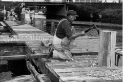 Building the pier on the canel,Kelly Smith shaping a bollard on the fisherman's jetty using an adze ,Portland.