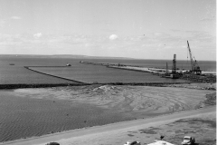 Construction of the K S A with th piles being driven in,note the dredge inthe bay pumping sand and rubble behind the wall when the water runs back into the sea the fill is left to be used to reclaim the area behind the wall.